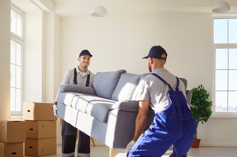 Cheerful,Man,Movers,Carrying,A,Sofa,During,A,Relocation,To
